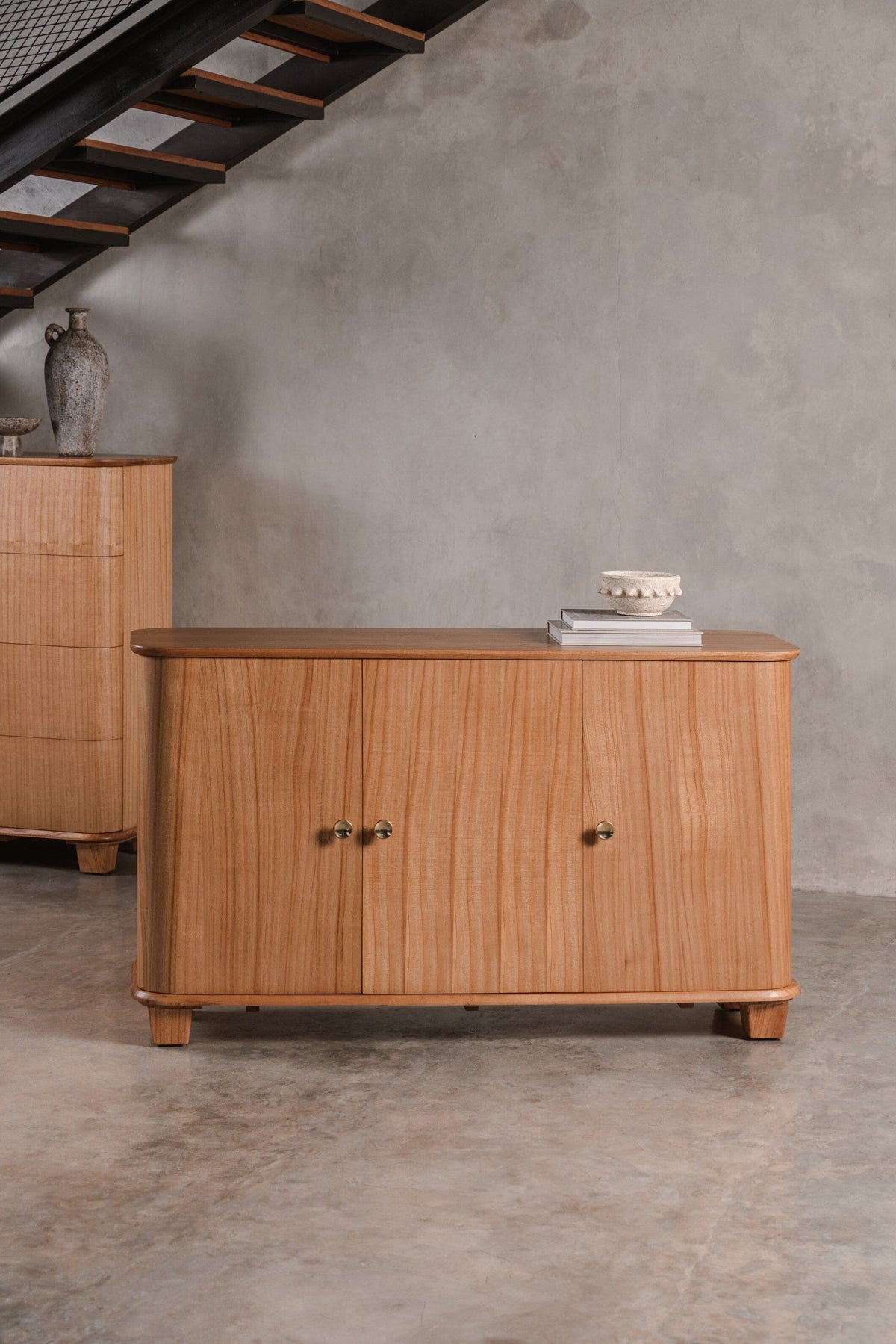 Wood buffet cabinet with two doors in a room with concrete floor and wall.