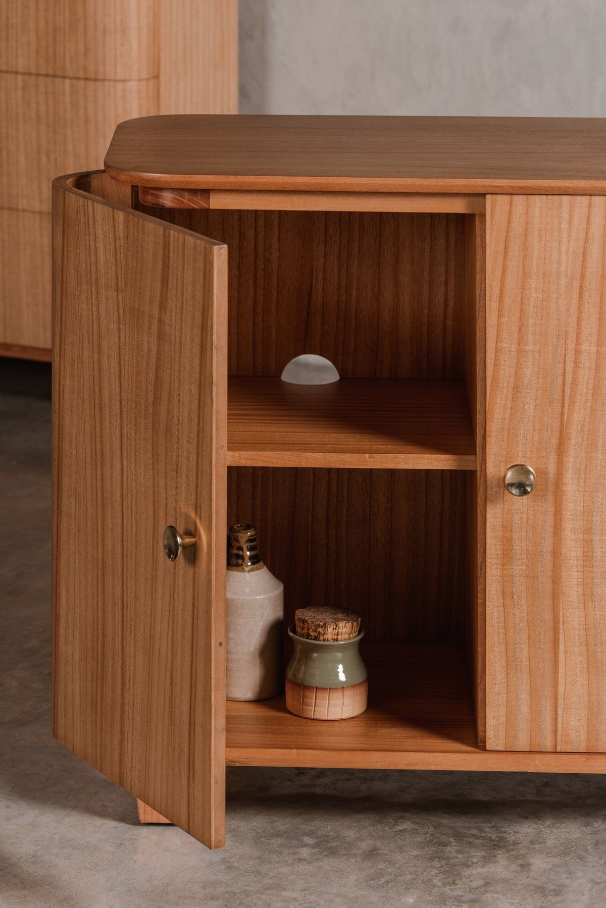 Hallway storage console with open door revealing spacious interior shelves and holes for wires.