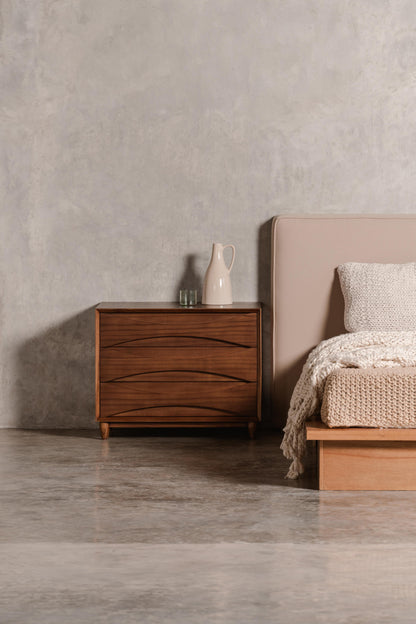 3 drawer beside table, wooden in a bedroom setting