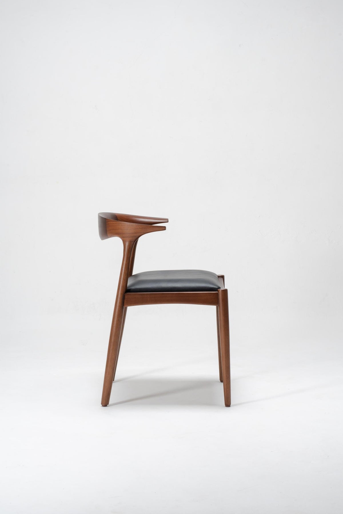 designer wooden dining room chair, with black leather seat